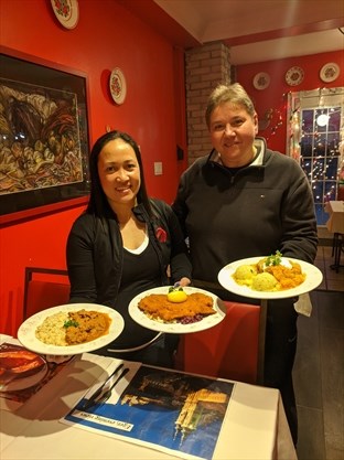 happy owners of Budapest restaurant, Toronto, holding dishes from their menu